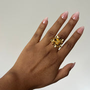 Gold flower ring shown on hand with white neutral background